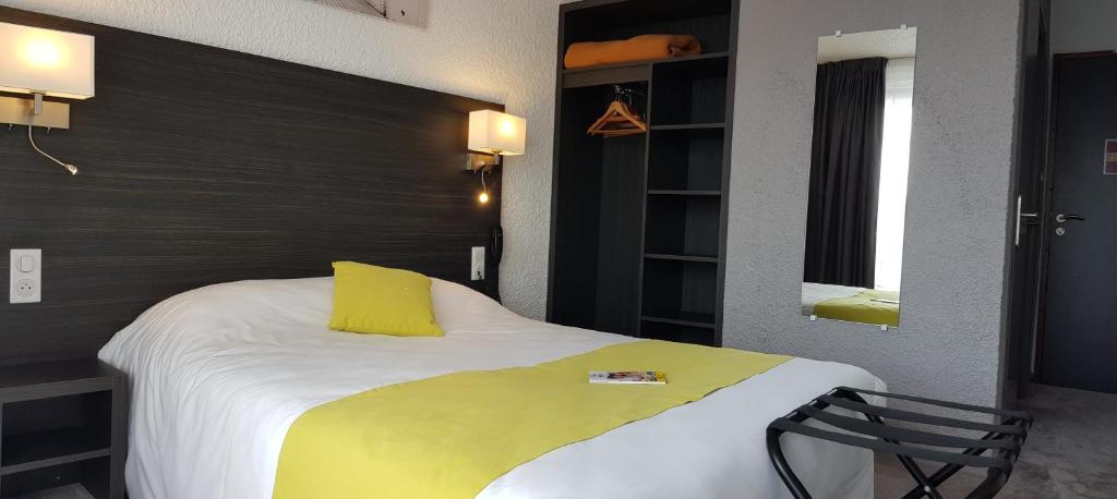 a bedroom with a large bed with a yellow pillow at Cit'Hotel Le Challans in Challans