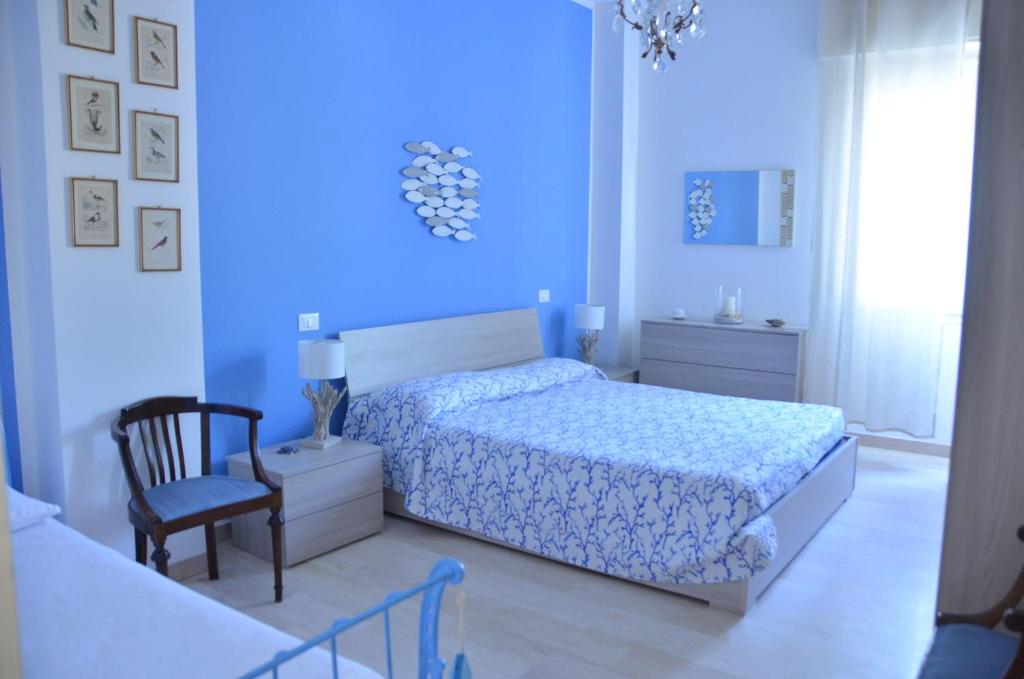 1 dormitorio azul con 1 cama y 1 silla en Una finestra sul Mare, en Laigueglia