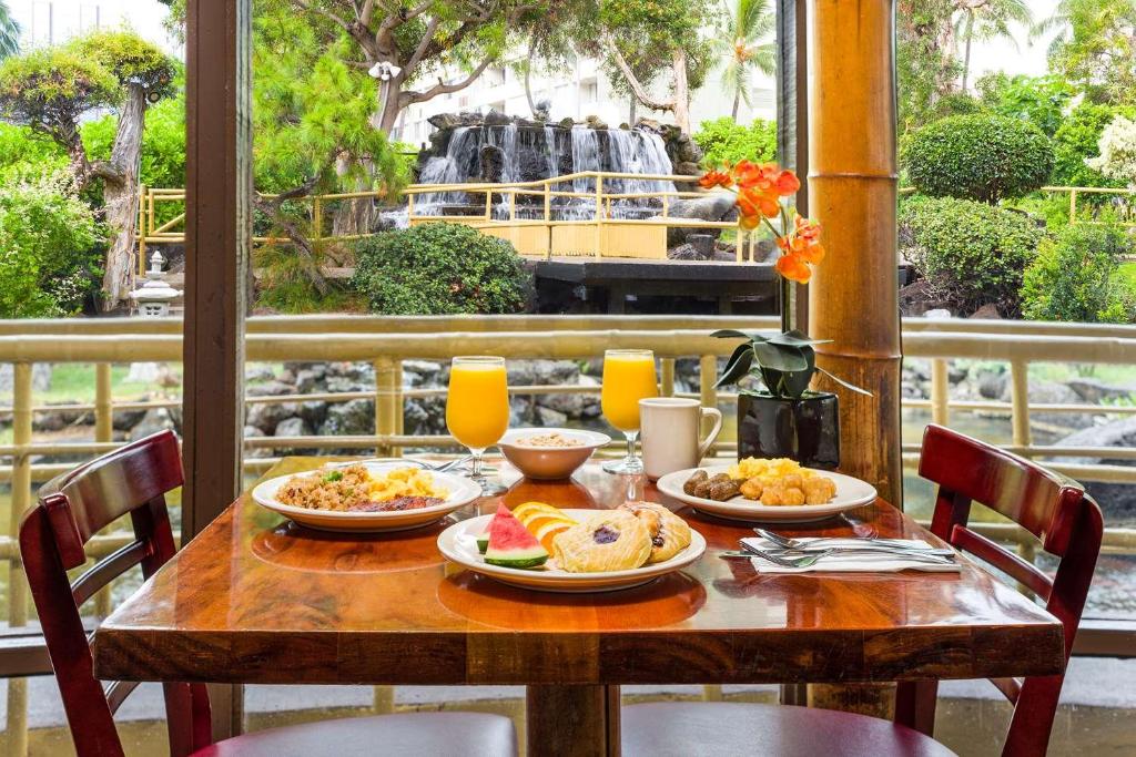 a wooden table with plates of food and a waterfall at Pagoda Hotel in Honolulu