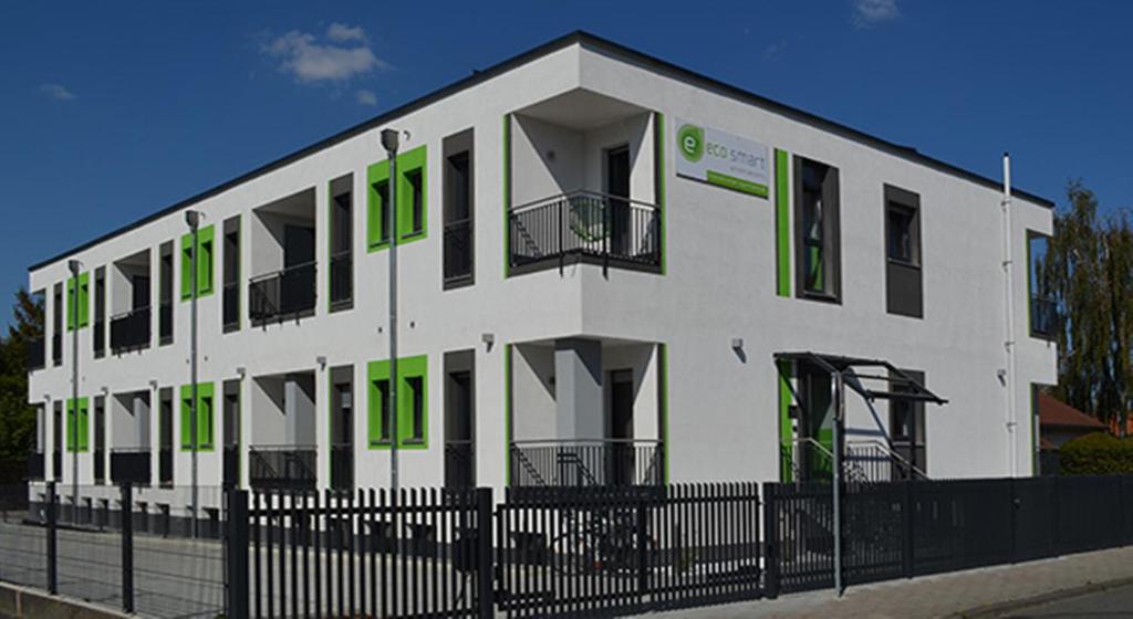 a white building with green windows and a fence at Eco Smart Apartments Erlangen in Erlangen