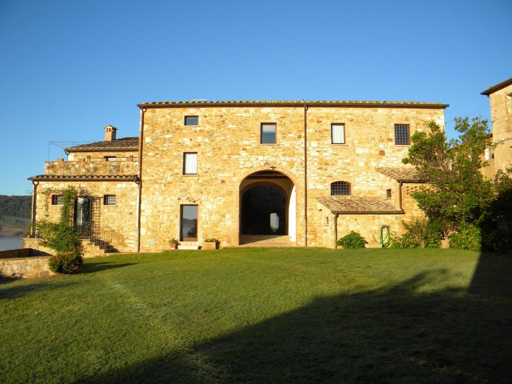 un grand bâtiment en briques avec une grande porte dans une cour dans l'établissement Agriturismo Tenuta il Tasso, à Rapolano Terme