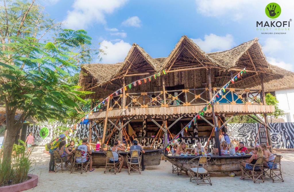 a group of people sitting at tables outside of a restaurant at Makofi Guest House in Nungwi