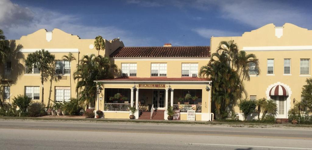 un grande edificio giallo con palme di fronte di Seminole Inn a Indiantown