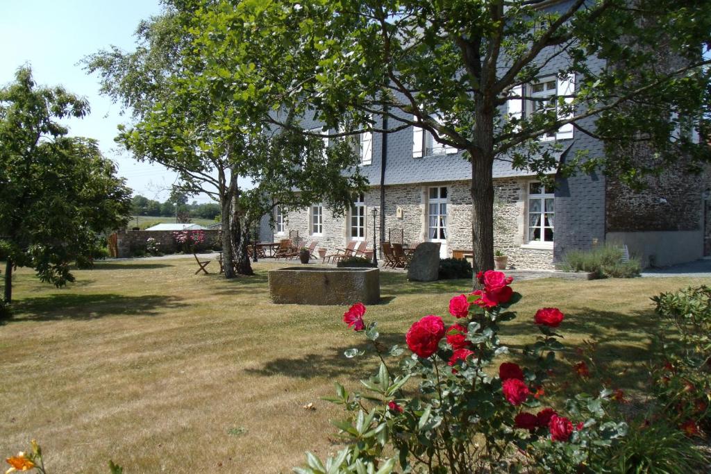 a stone house with red roses in the yard at LE TERTRE in La Feuillie