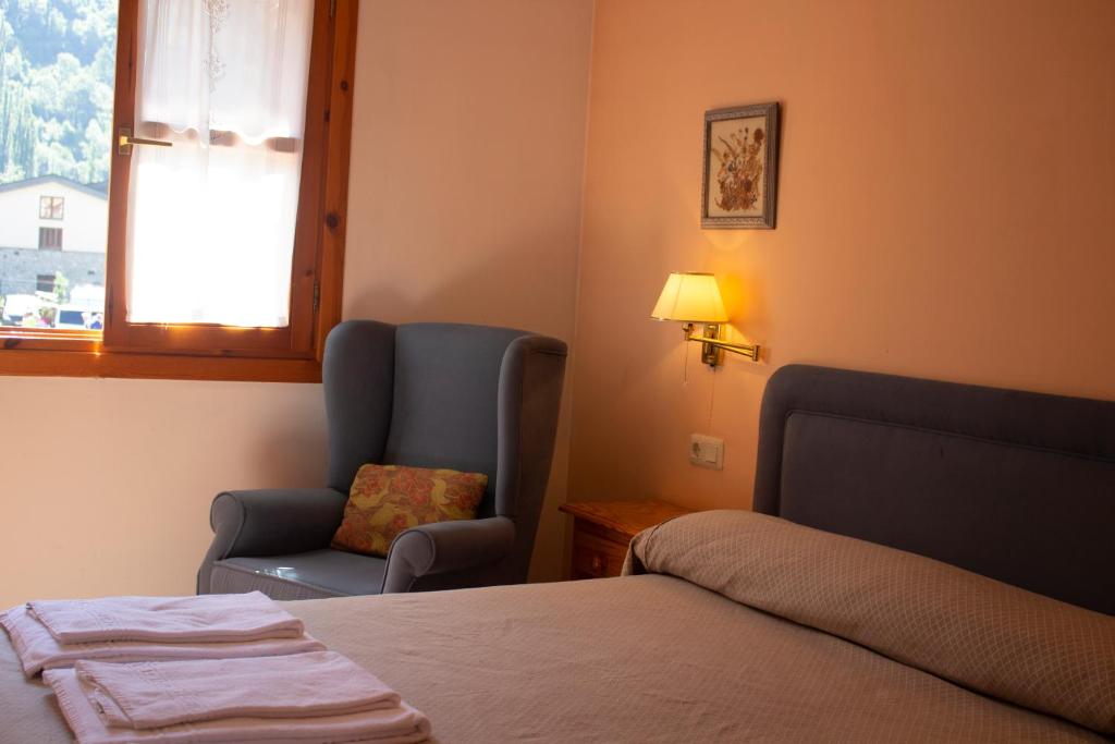 a bedroom with a bed and a chair and a window at Apartamentos Ball Benas Benasque in Benasque