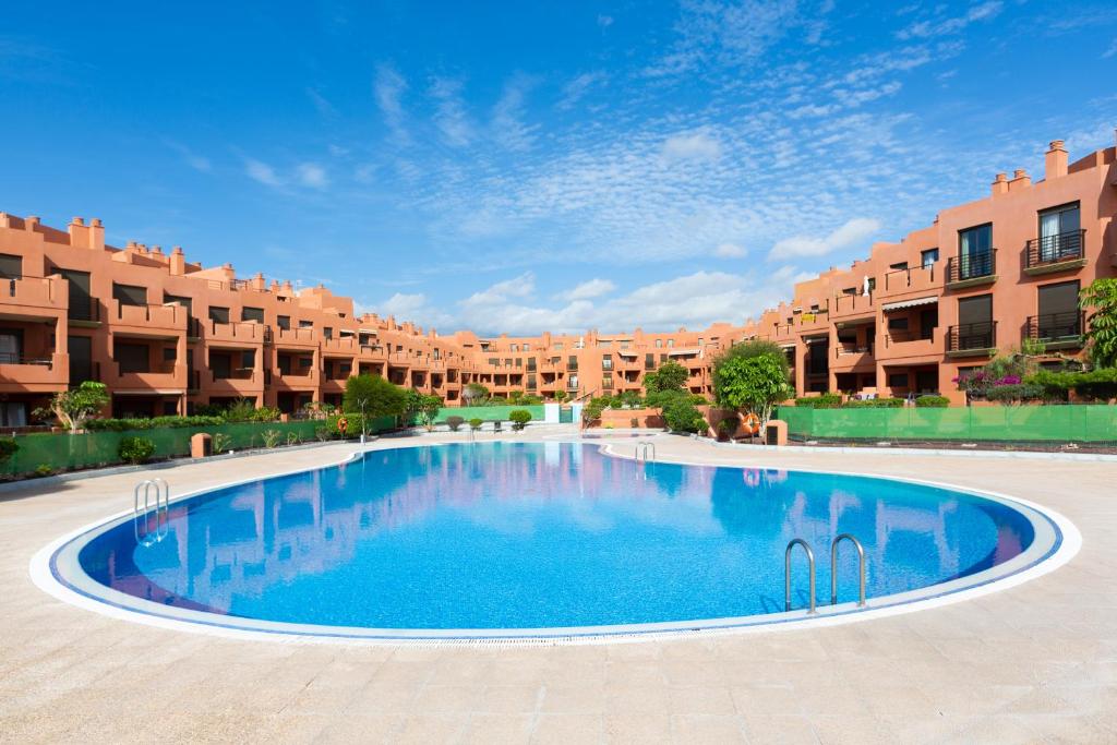 a large swimming pool in front of a building at Paradise palms Apartments in La Tejita