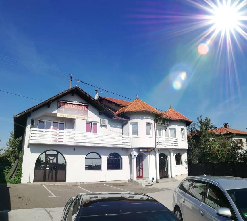 a white building with cars parked in front of it at Prenoćište SAMIR in Gradačac