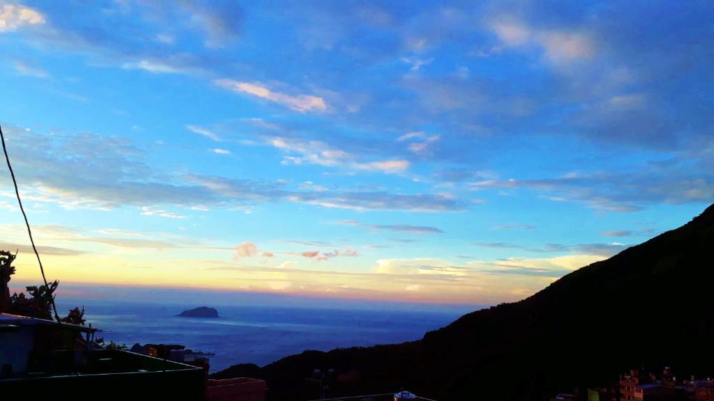 a view of the ocean from a mountain at sunset at Jiufen Breeze 九份惠風民宿ｌ6人包棟小屋 in Jiufen