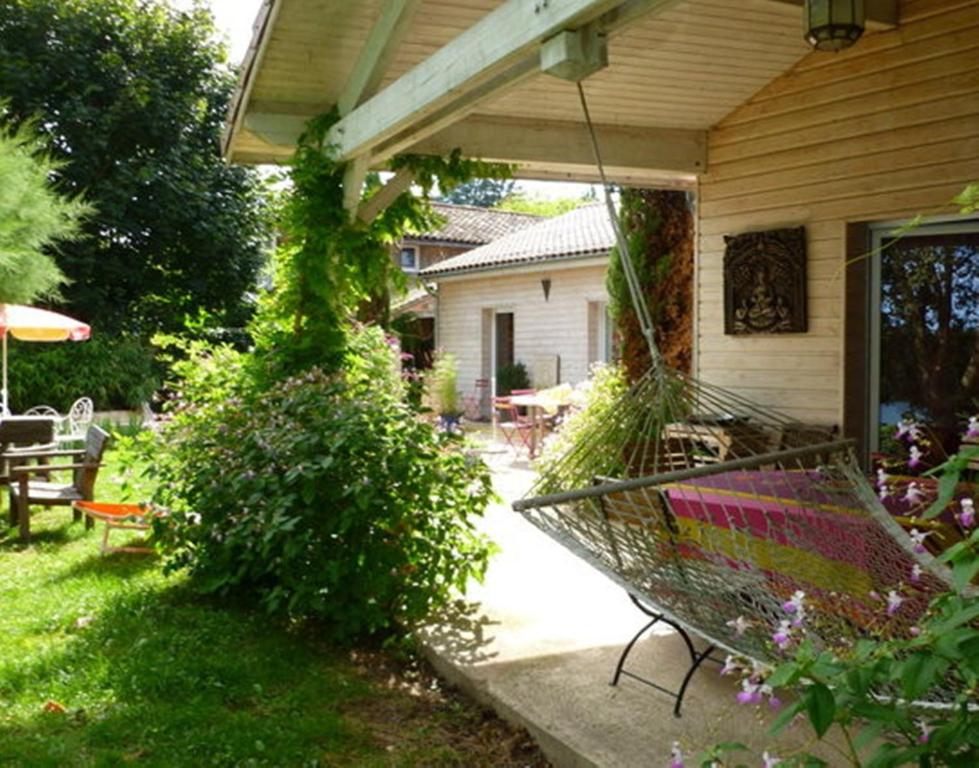 una hamaca colgada del porche de una casa en Chambre d'hôtes Au Fil de l'Eau, en Saint-Martin-Belle-Roche