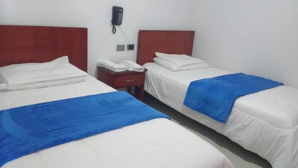 een kamer met twee bedden met blauw en wit bij Hotel Manzanares Baranoa in Baranoa