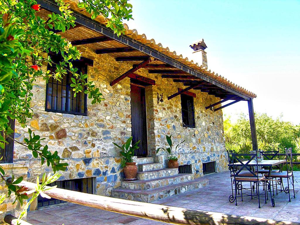 ein Steinhaus mit einem Tisch und Stühlen auf einer Terrasse in der Unterkunft La Casita de Piedra in Ronda