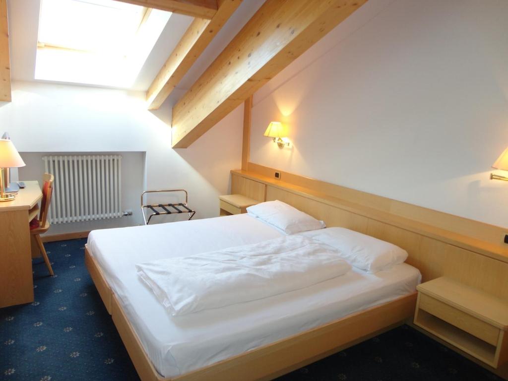 a bedroom with a white bed and a desk at Garni Aritz in Campitello di Fassa