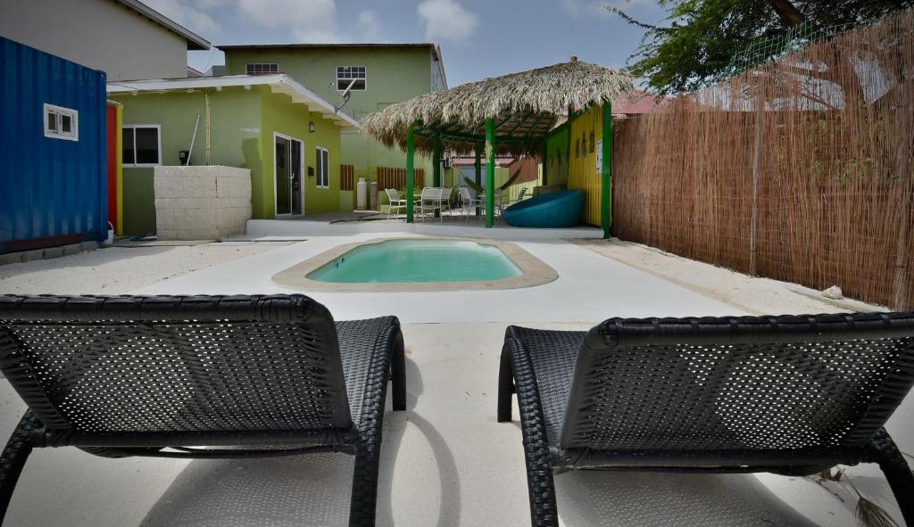 twee stoelen en een zwembad in de tuin bij Pista Q hostel and apartments in Oranjestad