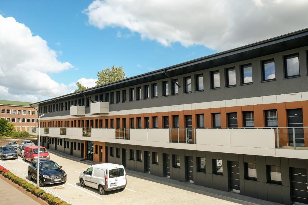 un edificio de oficinas con coches estacionados en un estacionamiento en Apartments A7, en Hamburgo