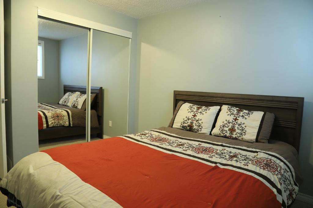 a bedroom with a bed with an orange blanket at Sweet Home In Calgary in Calgary