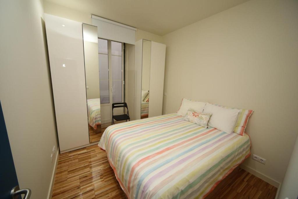 een kleine slaapkamer met een bed met een gestreepte deken bij Casa de Santa Marta in Lissabon