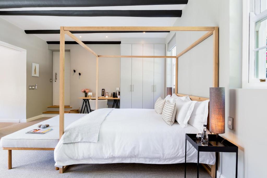 a bedroom with a white bed with a wooden frame at Maison Cabrière - Boutique Suites in Franschhoek