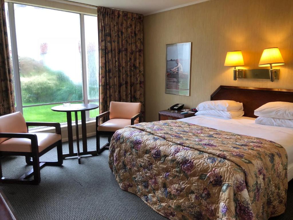 um quarto de hotel com uma cama, uma mesa e cadeiras em Gateway Inn em Merrick