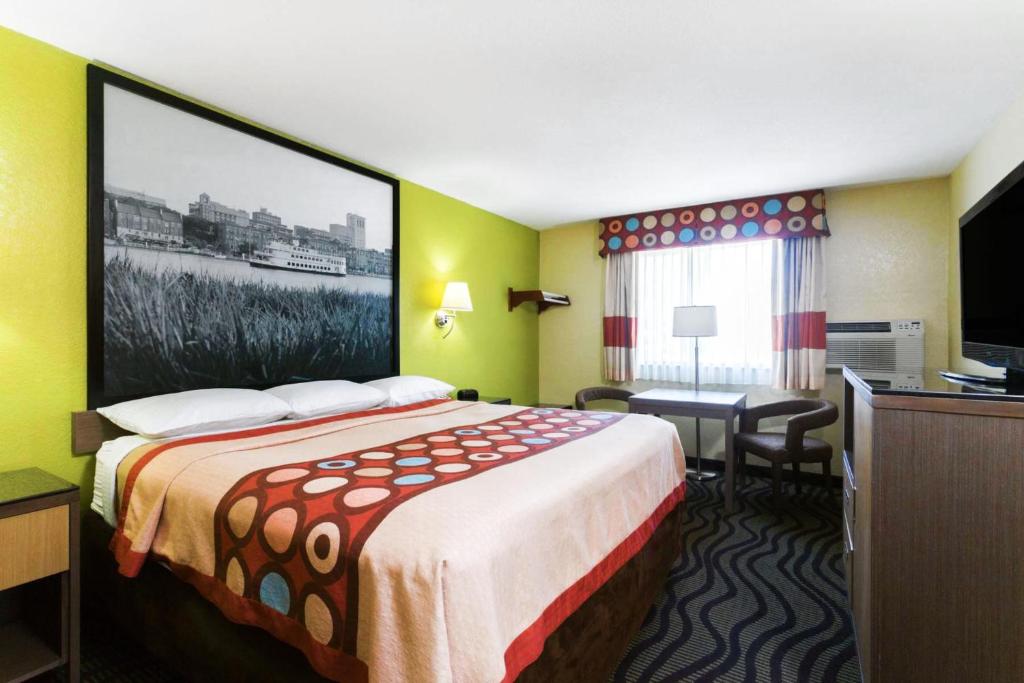 a hotel room with a bed and a large picture on the wall at Super 8 by Wyndham Brunswick/St Simons Island Area in Brunswick