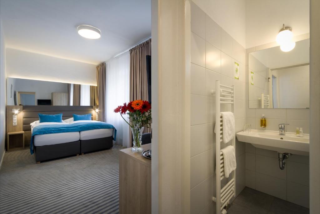 プラハにあるHotel White Lionのベッドとシンク付きのホテルルーム