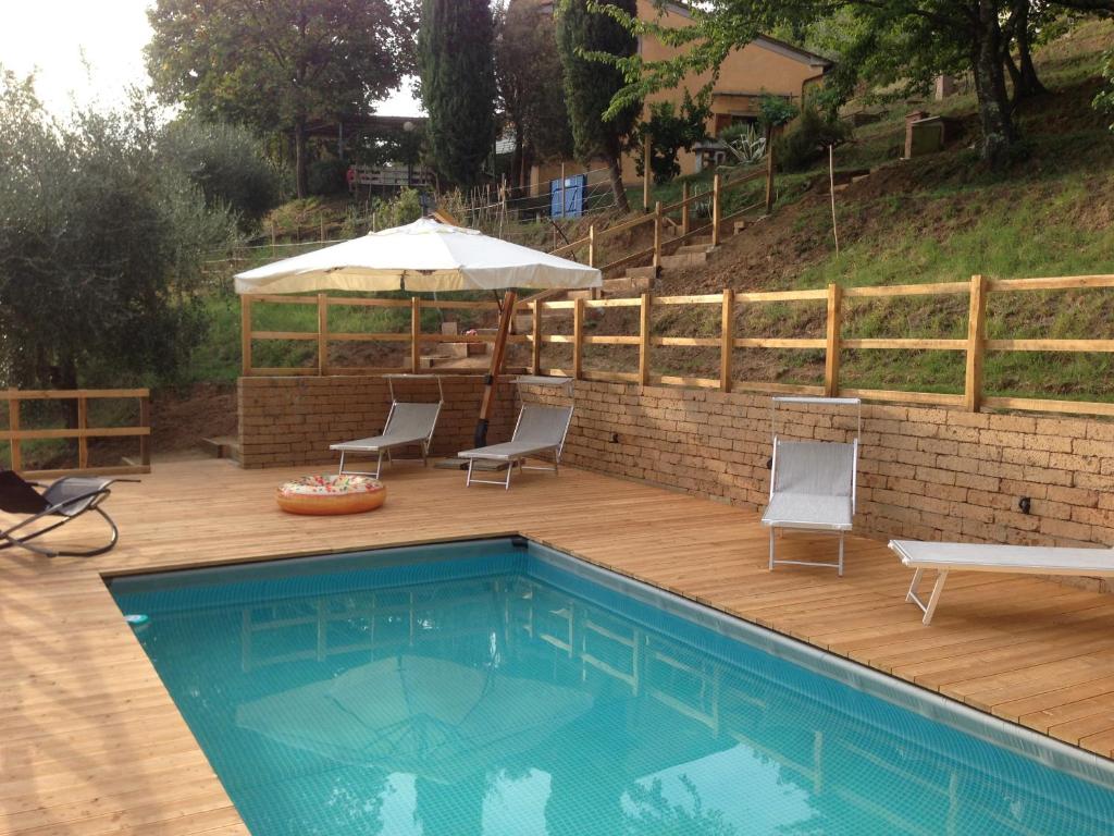 a swimming pool with chairs and an umbrella on a wooden deck at La Casa sui Colli in Uzzano