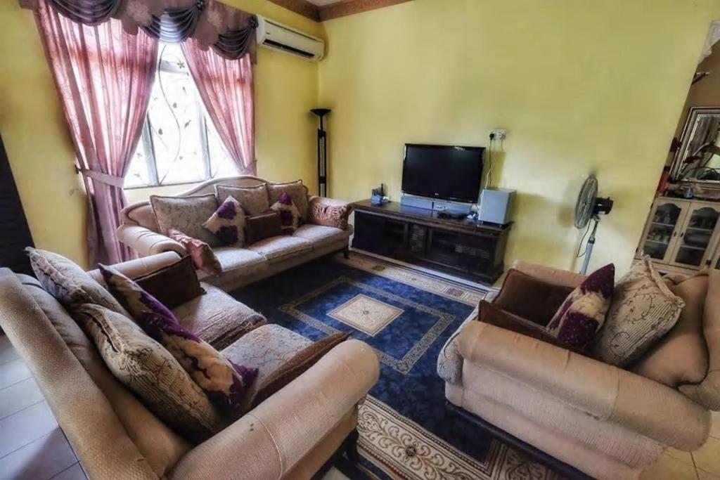a living room with couches and a flat screen tv at Homestay Jasmin Indah, Senawang (free wifi) in Seremban
