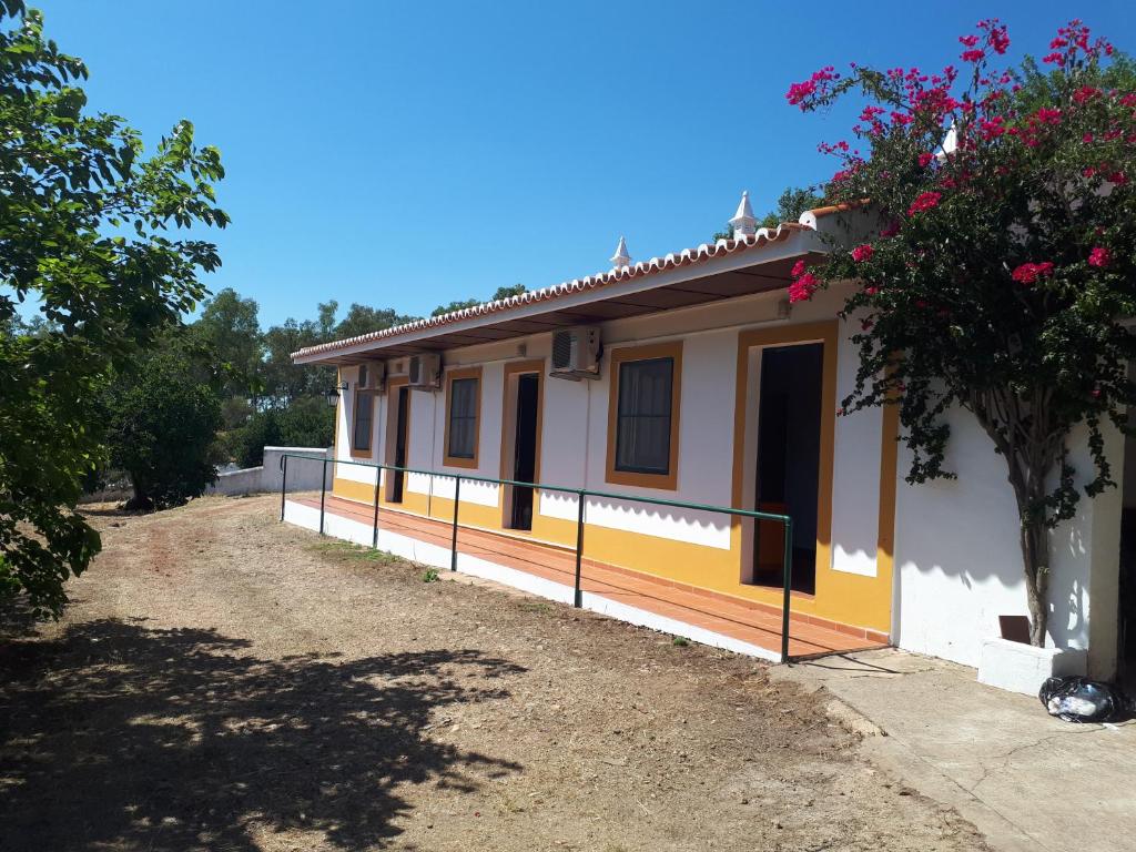 una pequeña casa blanca y amarilla con un árbol en Palacete Dos Alcaides en Minas de São Domingos
