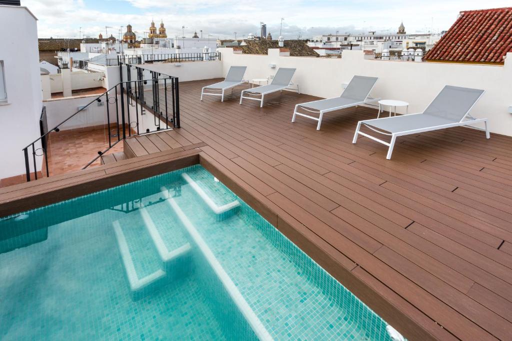 a rooftop deck with a swimming pool and chairs at Apartamentos Lanza in Seville