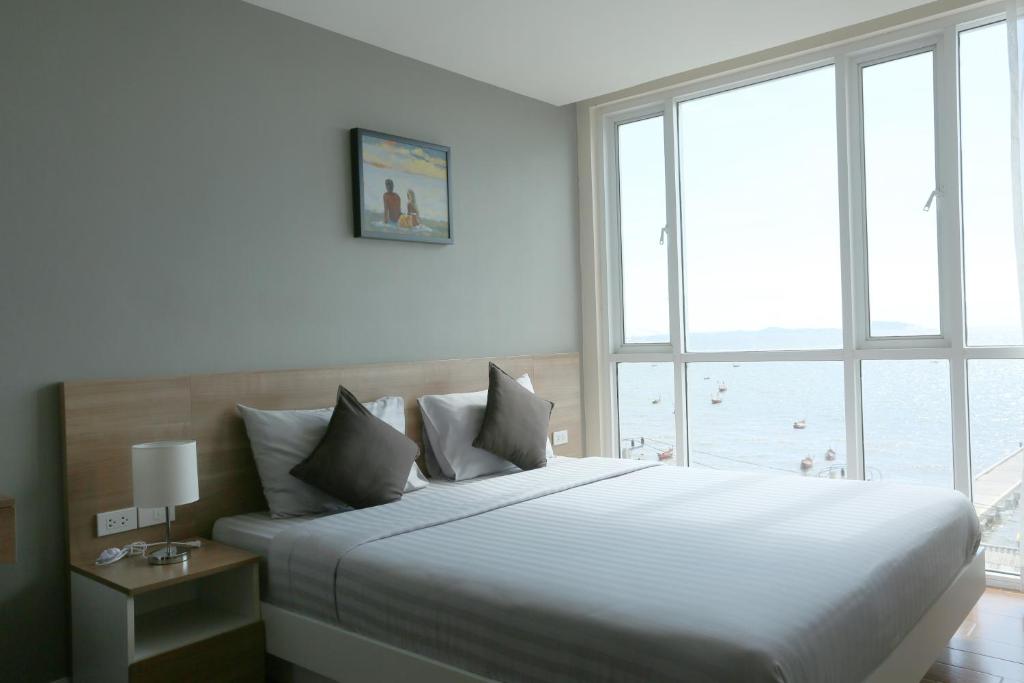 a bedroom with a large bed with a large window at BBG Seaside Luxurious Service Apartment in Bangsaen