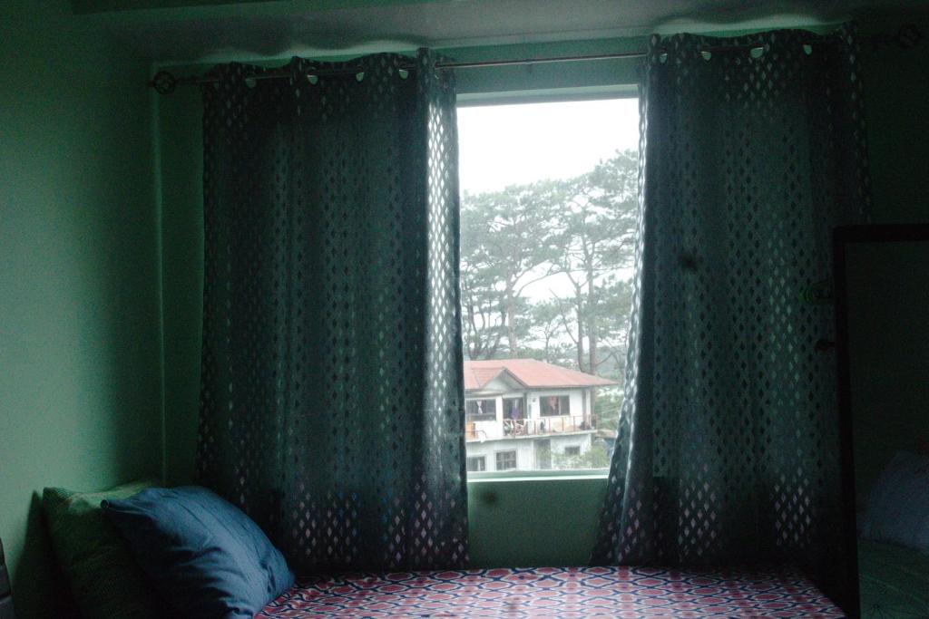 a bedroom with a window with a view of a house at Albergo Condotel - AB Pagadian Enterprise in Baguio