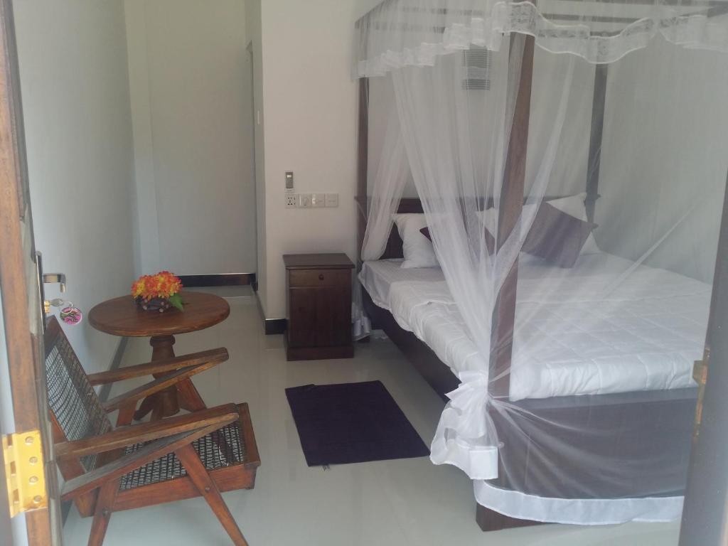 1 dormitorio con cama con dosel y mesa de madera en Senu Home, en Weligama