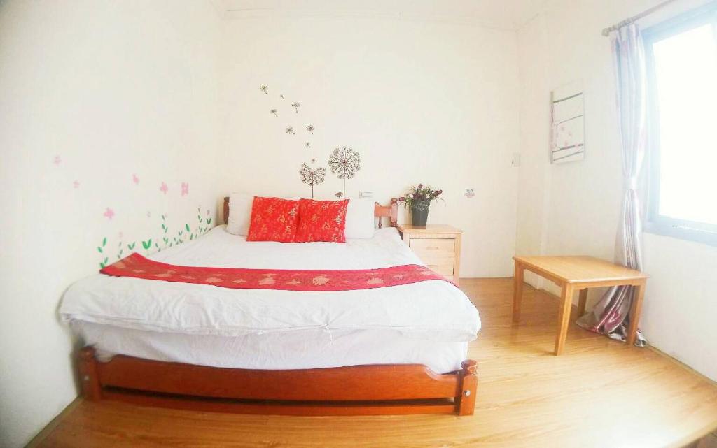a bedroom with a bed with red pillows on it at Ding Ding Homestay in Jinhu