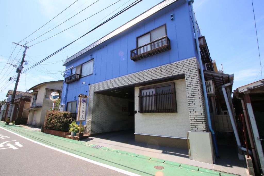 un edificio azul al lado de una calle en Ryokan Kibun en Tsuiki