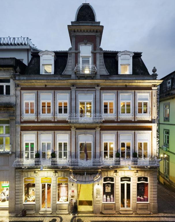 un vieux bâtiment avec une horloge en haut dans l'établissement Grande Hotel do Porto, à Porto
