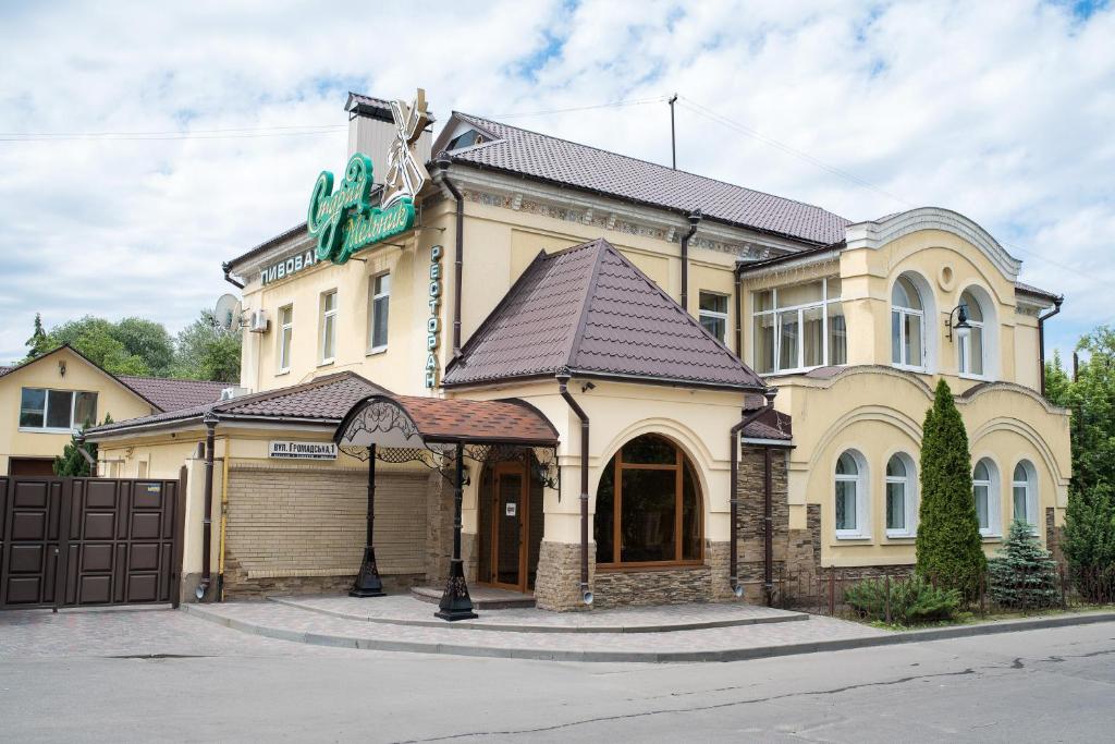 ein großes gelbes Gebäude mit einem Tor davor in der Unterkunft Restoran-hotel Stariy Melnik in Poltawa