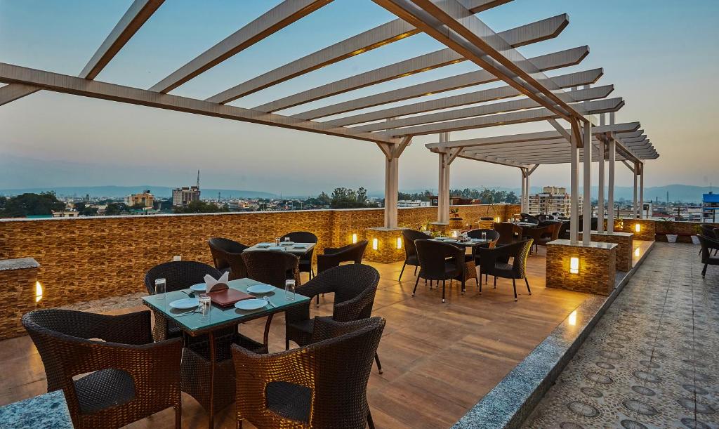 Treebo Trend Grand Legacy Elite With Roof Top Cafe في دهرادون: مطعم بطاولات وكراسي على السطح