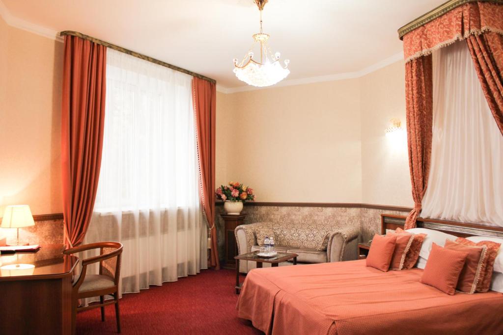 um quarto de hotel com uma cama, um sofá e uma janela em Empire Hotel em Irkutsk