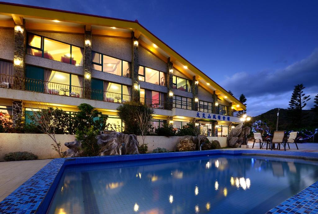 a hotel with a swimming pool in front of a building at Da Jen Shan Style Resort in Kenting