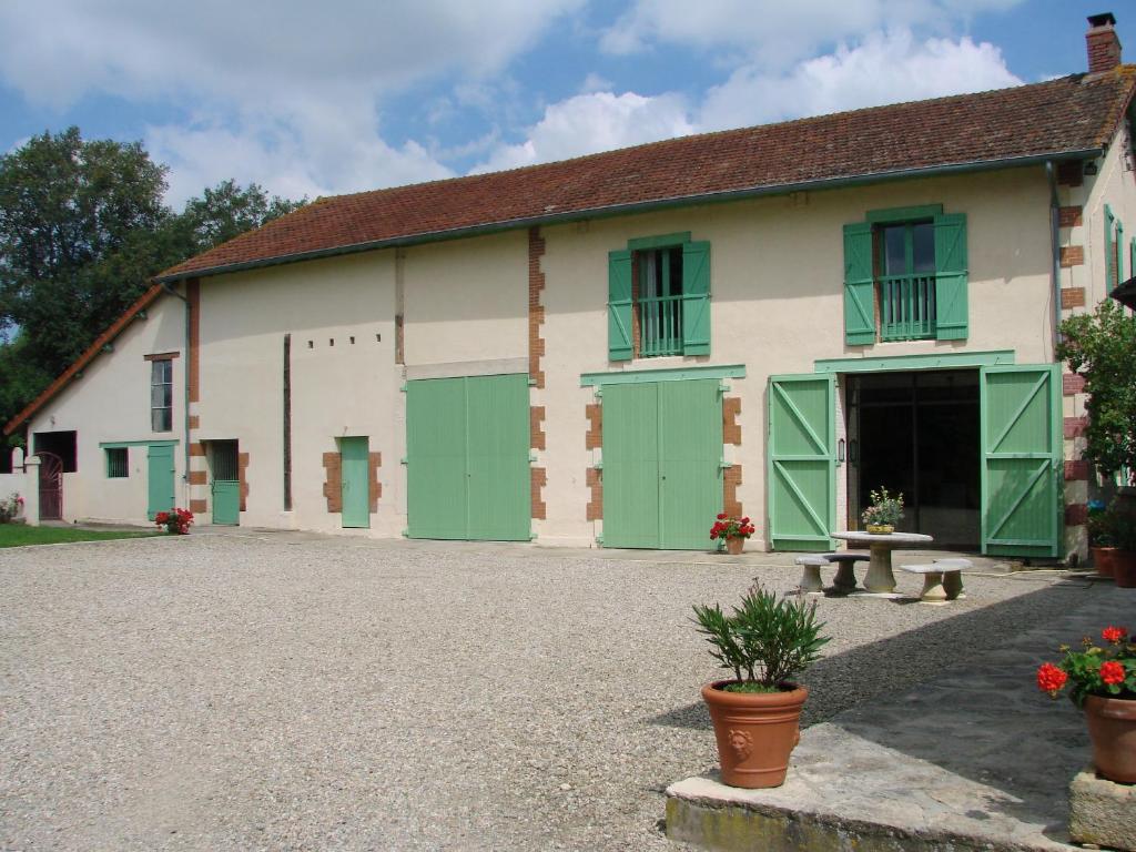 un bâtiment avec des portes vertes et un banc à l'avant dans l'établissement Les Malvaux, à Huriel