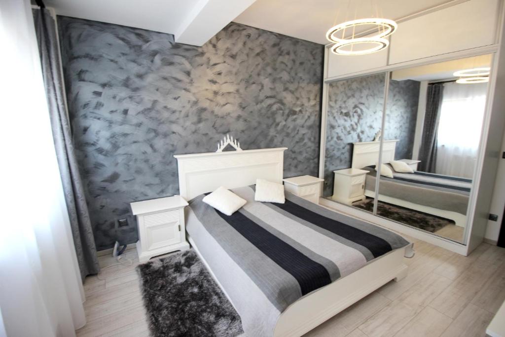 - une chambre avec un lit et un grand miroir dans l'établissement Apartament Diana, à Târgu-Mureş