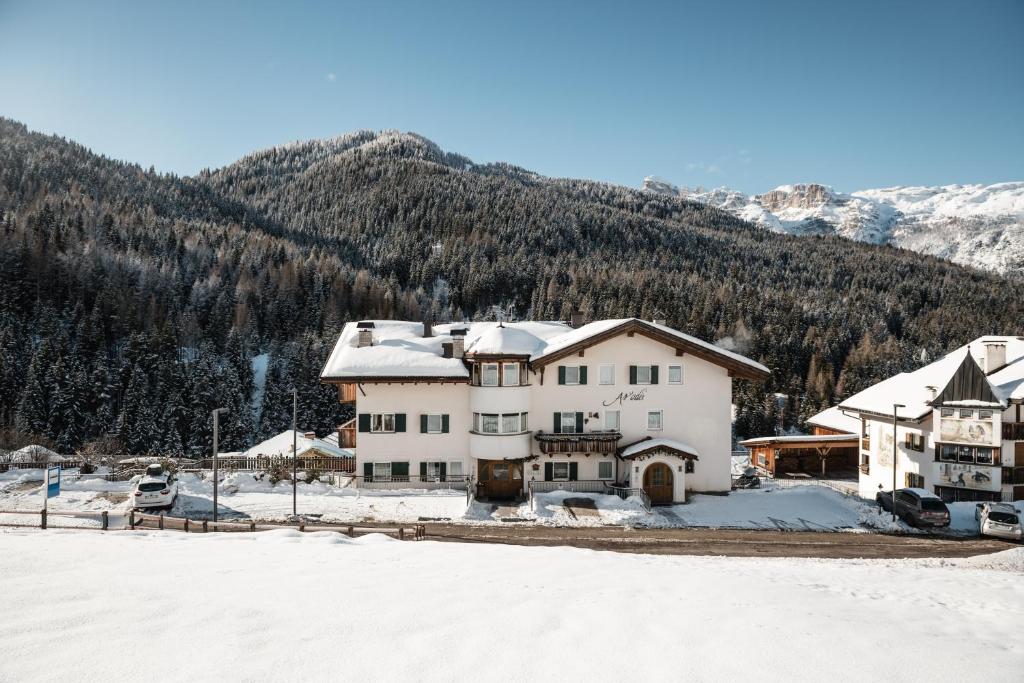 een huis in de sneeuw met bergen op de achtergrond bij Residence As'Odei in San Cassiano