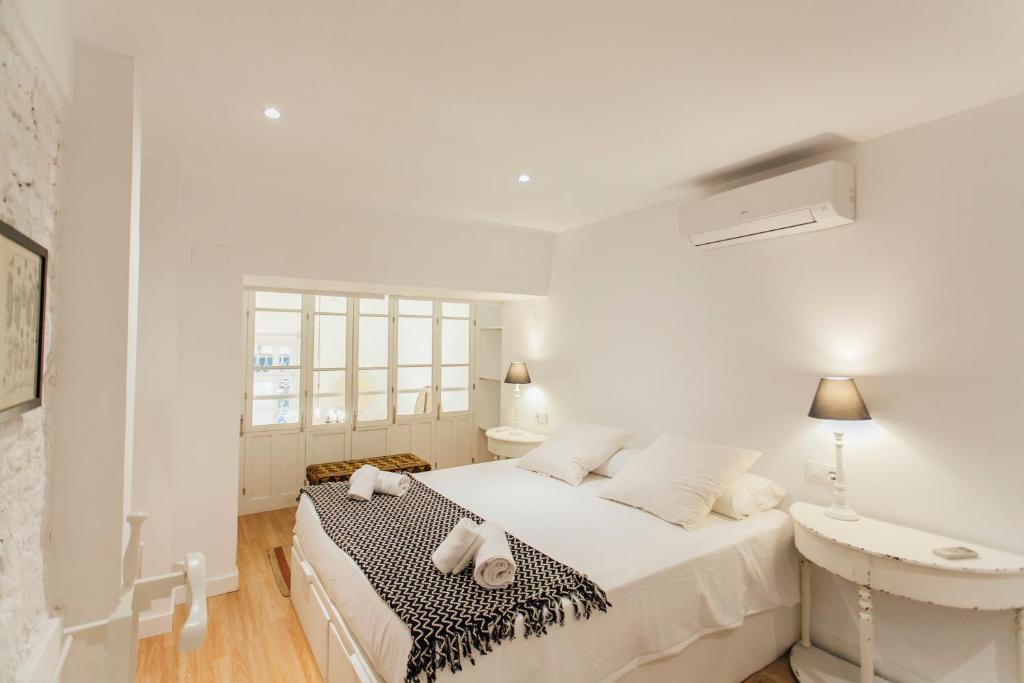 a white bedroom with a bed and a table at CSE Pajaritos in Seville