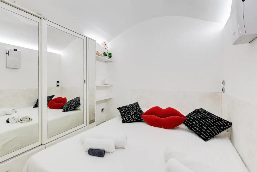 a white bedroom with red pillows and a mirror at Cherì Navona in Rome