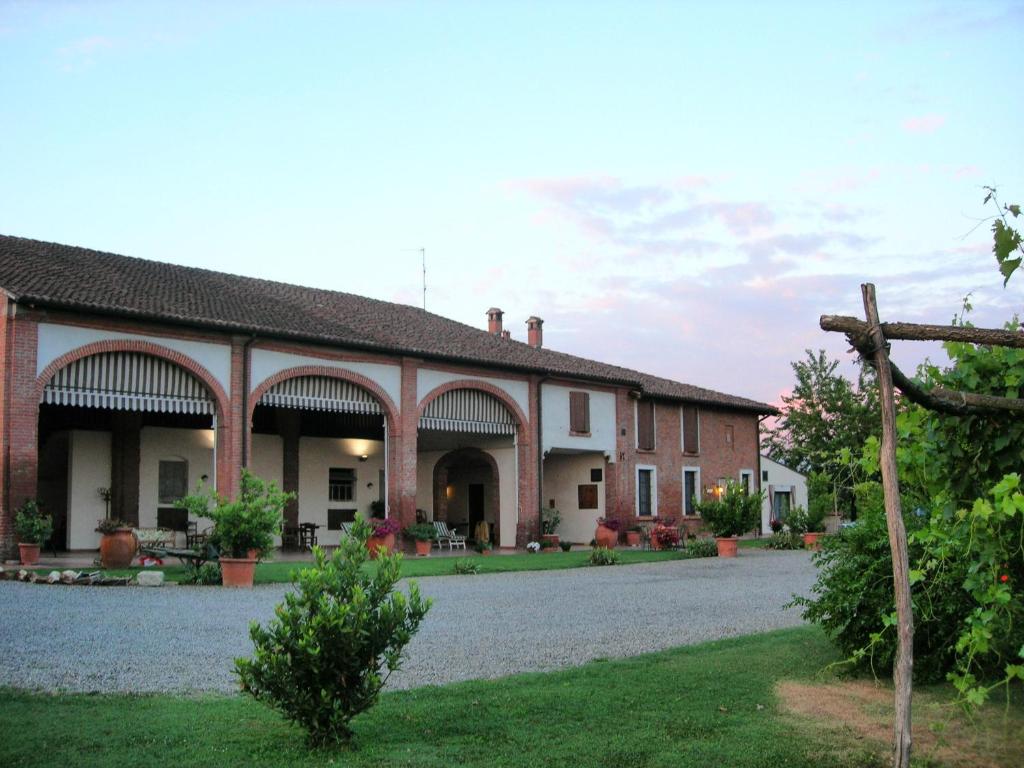 un grand bâtiment en briques avec des arches et une cour dans l'établissement Agriturismo Campass, à Castelvetro Piacentino