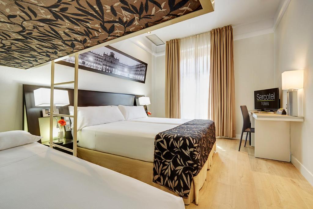 サラマンカにあるセルコテル ラス トーレスのベッド2台とデスクが備わるホテルルームです。