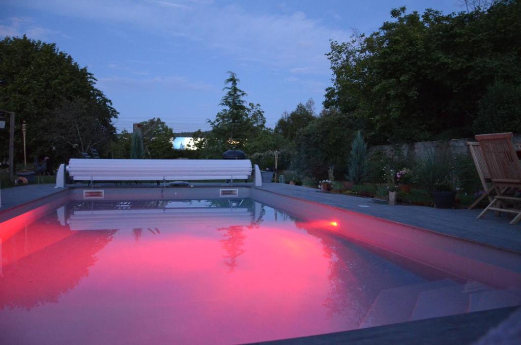 - une piscine avec des lumières rouges dans une arrière-cour la nuit dans l'établissement 23 Avenue Pasteur, à Saint-Julien-du-Sault