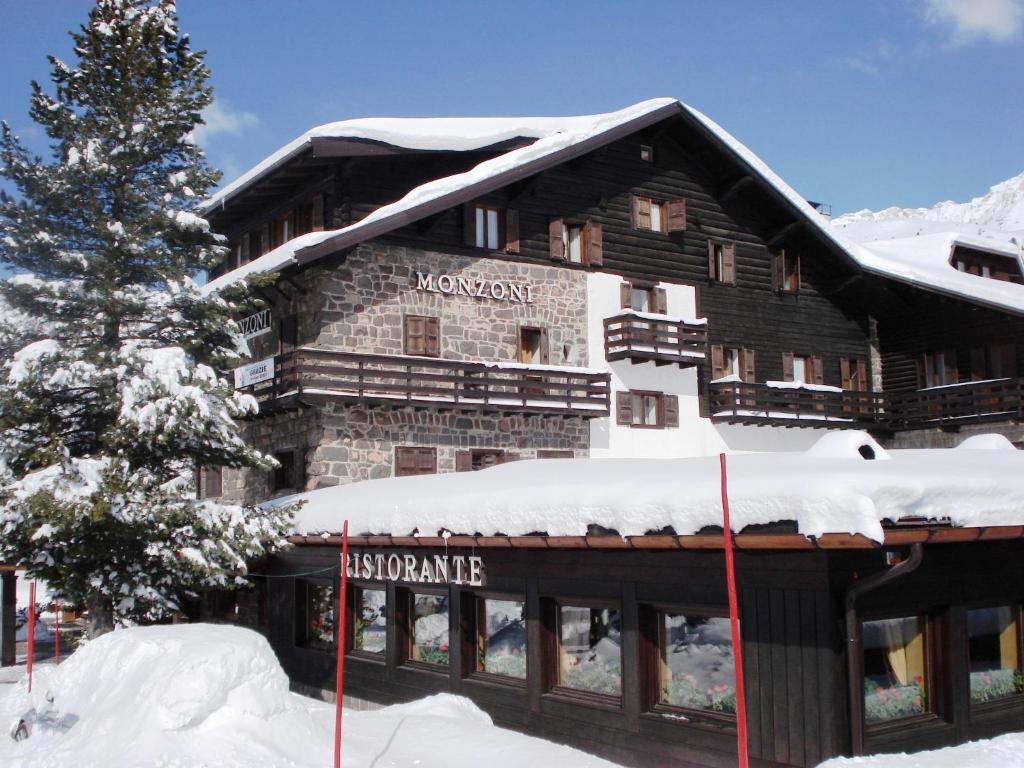 un grande edificio con la neve sopra di esso di Hotel Monzoni - San Pellegrino a Passo San Pellegrino