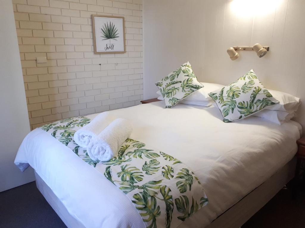 a bedroom with a white bed with green and white pillows at Villa Eight in Kalbarri