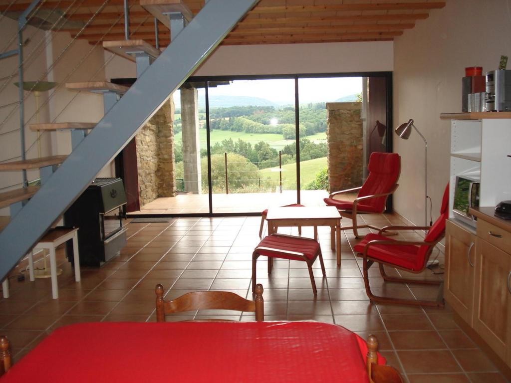 a living room with red chairs and a staircase at Gîte du Tarbésou in Régat