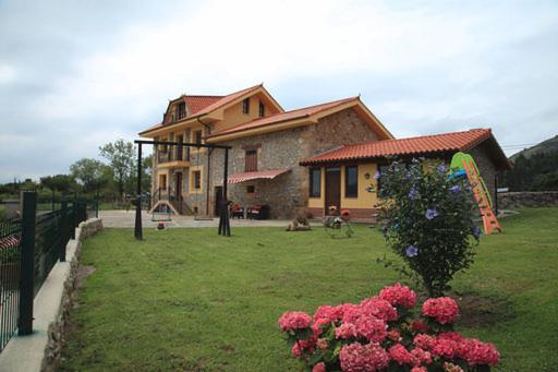 una casa con una cometa en un patio con flores en Vivienda Rural La Mazuga, en Cabárceno